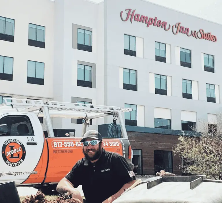 Double L Plumbing technician performing commercial plumbing work outside a Hampton Inn & Suites in North Texas