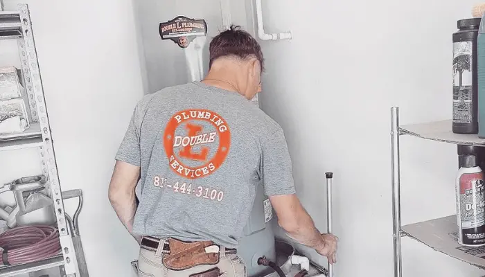 Double L Plumbing technician servicing a water heater in Azle, TX.