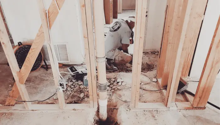 Plumber installing plumbing lines during early stages of new home construction