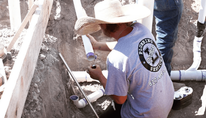 Double L Plumbing technician installing new PVC plumbing lines during a residential repiping project in North Texas.