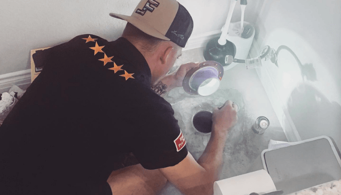 A professional plumber inspecting a bathroom drain to evaluate plumbing performance and identify potential system issues.